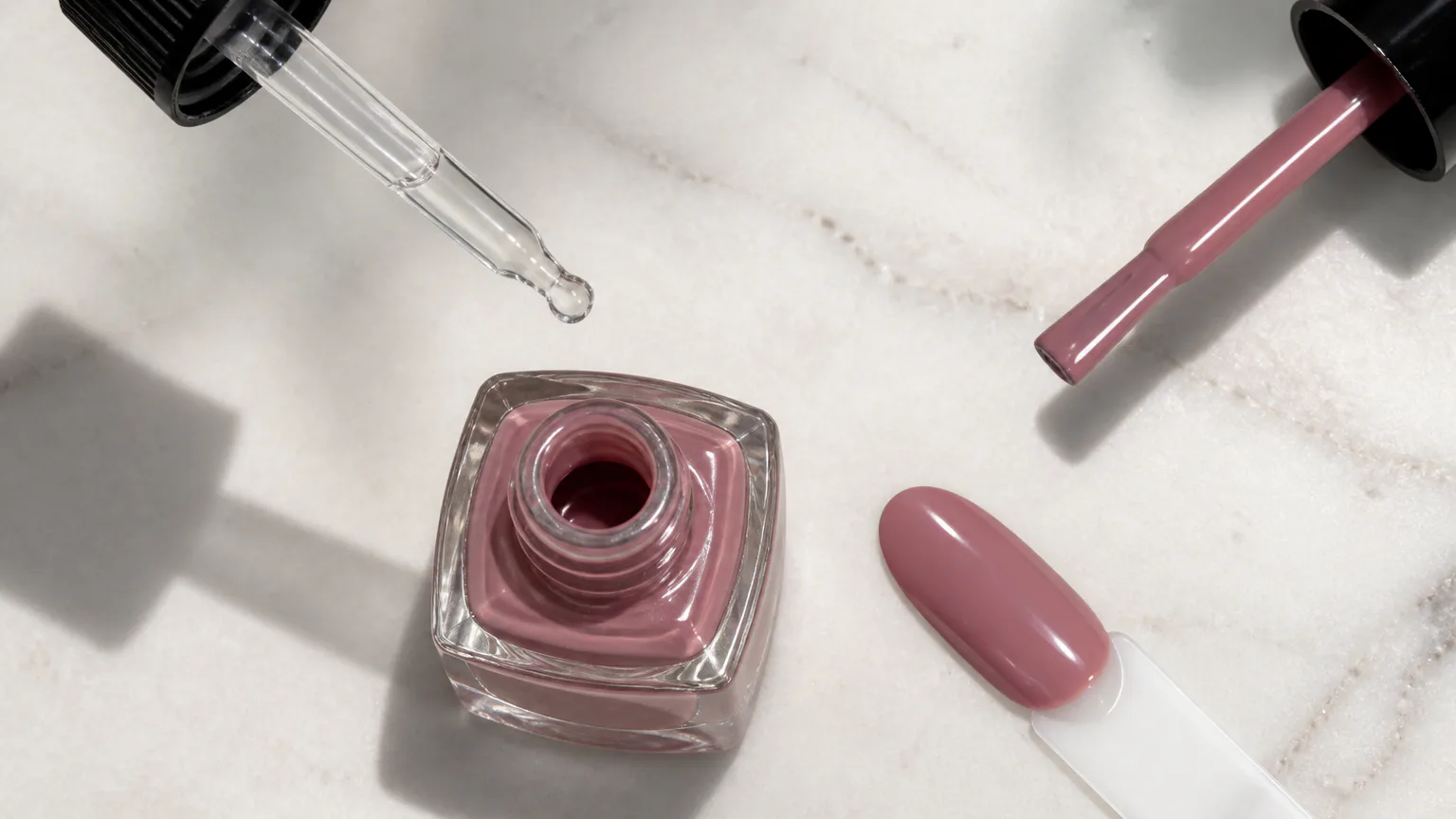 Pink nail polish bottle, brush, and swatch