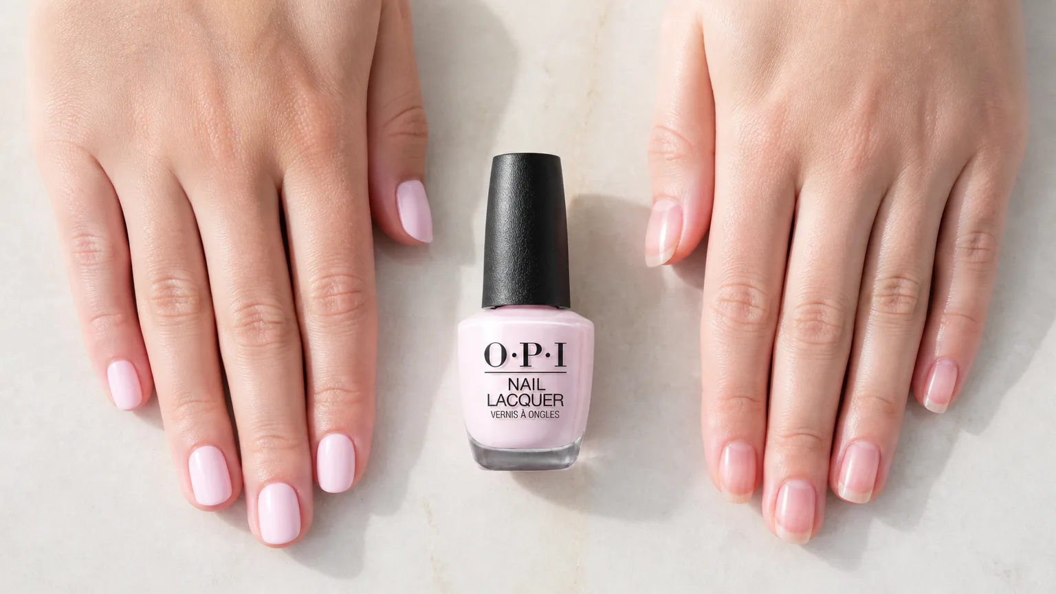 Hands with pink nail polish and an OPI bottle